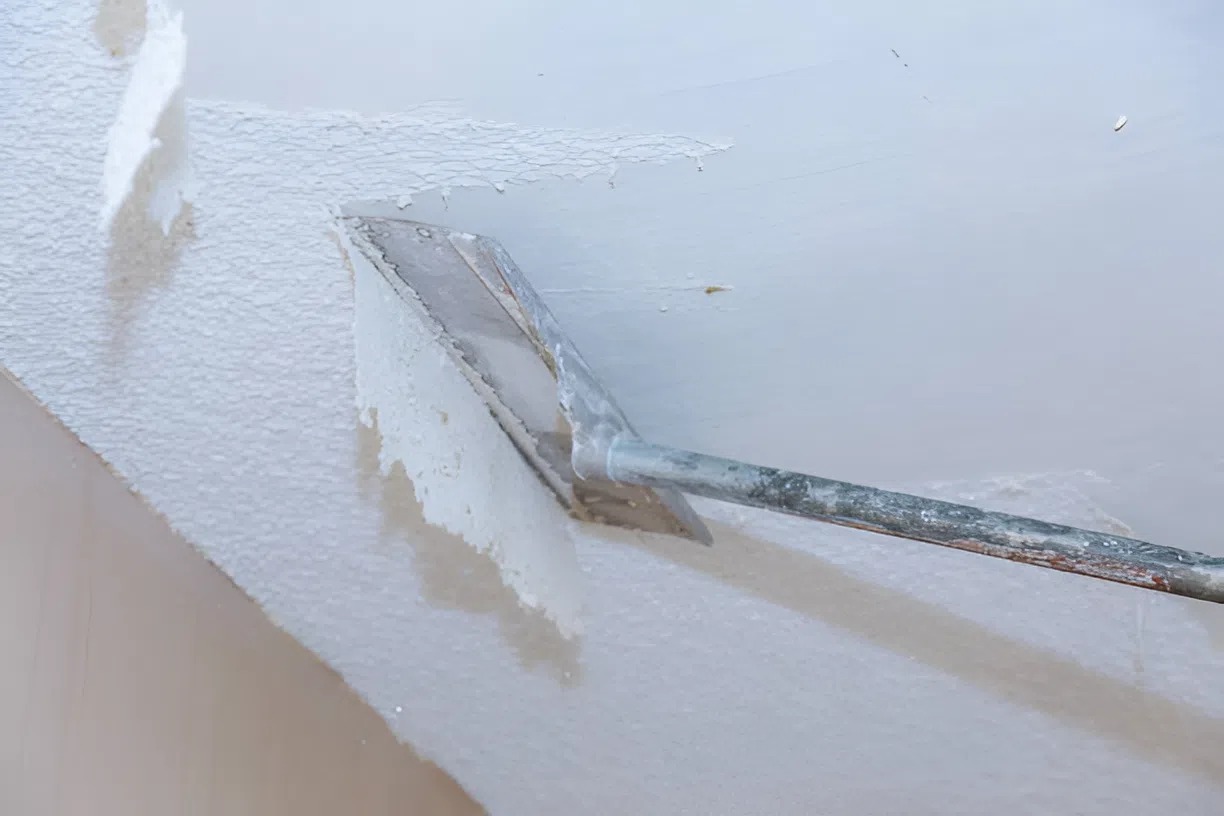 Contractor scraping popcorn ceiling texture during removal process by an interior painter in Kalamazoo, MI